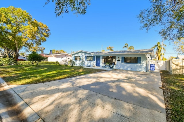 single story home with concrete driveway, a front lawn, and fence