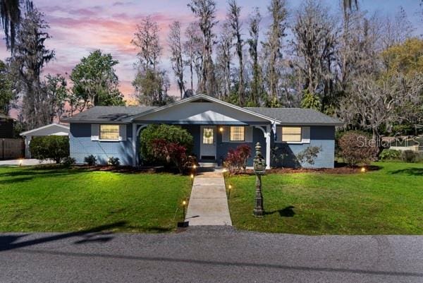 ranch-style home featuring driveway, a lawn, and brick siding