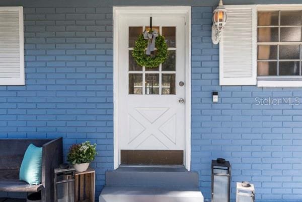 view of exterior entry featuring brick siding