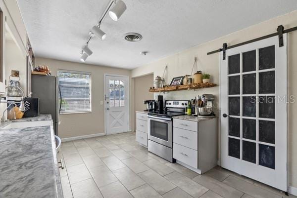 kitchen with a textured ceiling, open shelves, appliances with stainless steel finishes, and a barn door