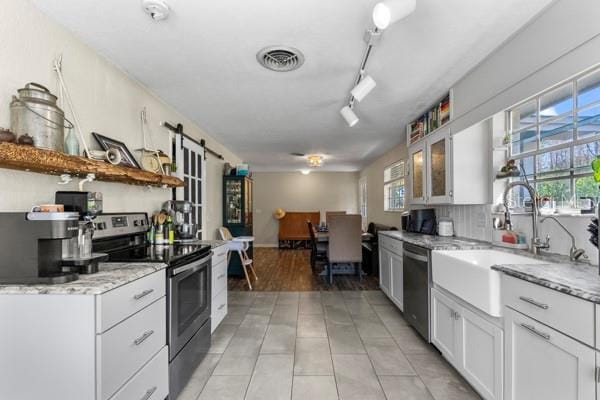 kitchen featuring a barn door, visible vents, white cabinets, appliances with stainless steel finishes, and open shelves