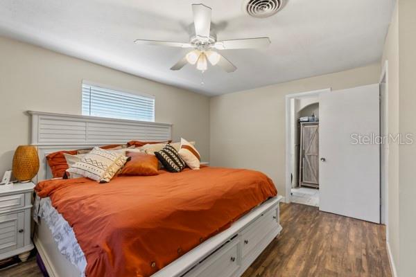 bedroom with ceiling fan, dark wood finished floors, and visible vents