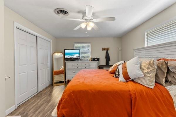 bedroom featuring a closet, wood finished floors, visible vents, and a ceiling fan