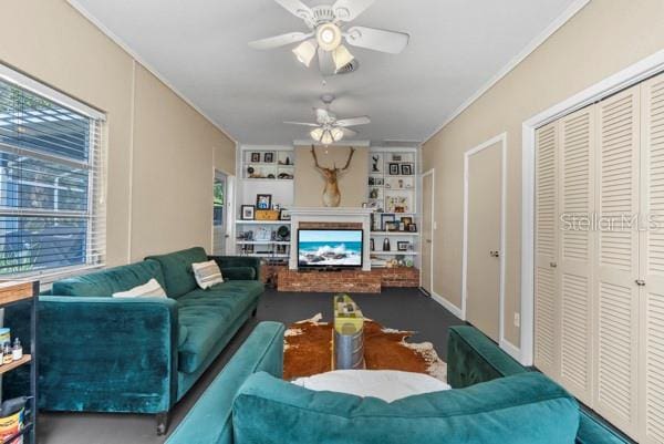 living room with a ceiling fan, a brick fireplace, and crown molding