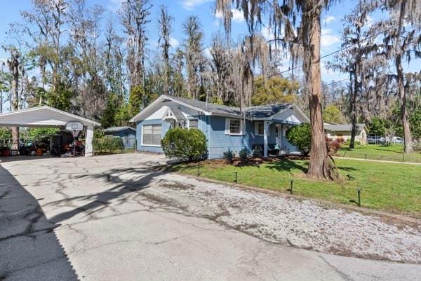 view of front of property with a detached carport, driveway, and a front lawn