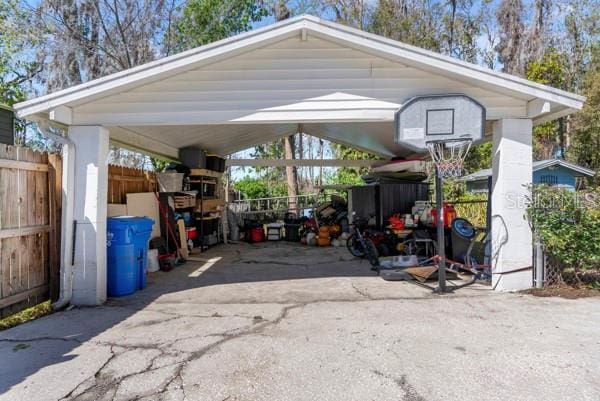 view of parking / parking lot with a carport and fence