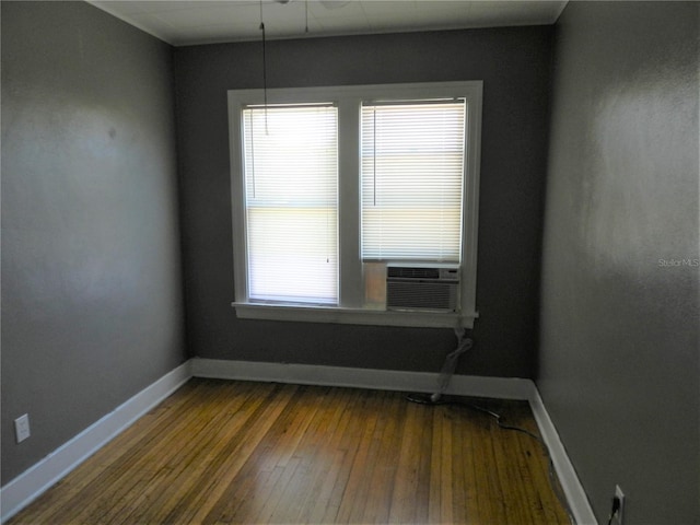 unfurnished room featuring a healthy amount of sunlight, cooling unit, baseboards, and hardwood / wood-style floors