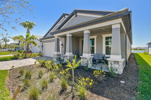 view of front of house featuring a porch, an attached garage, driveway, and stucco siding