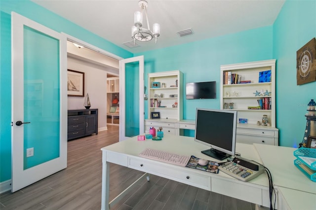 office space with an inviting chandelier, wood finished floors, and visible vents