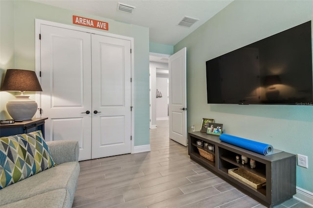 living area featuring baseboards, visible vents, and wood tiled floor