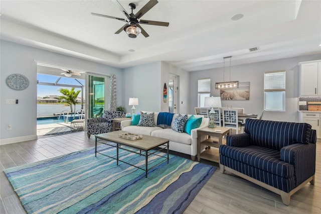 living area with visible vents, baseboards, a ceiling fan, and light wood finished floors