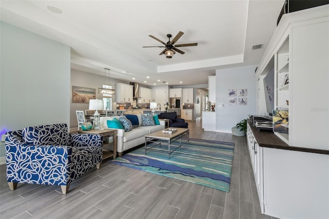 living area featuring visible vents, ceiling fan, wood tiled floor, recessed lighting, and a raised ceiling