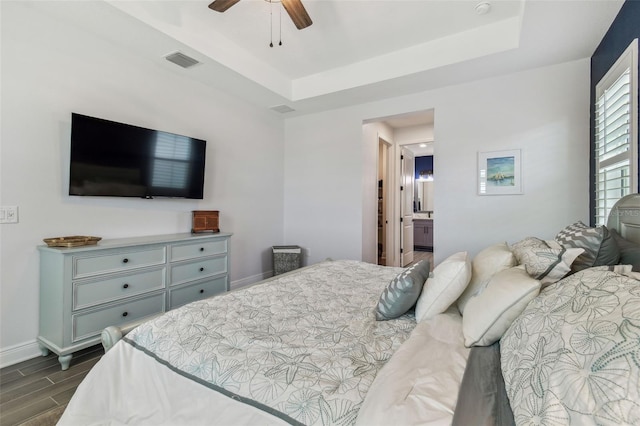 bedroom featuring a tray ceiling, visible vents, baseboards, and wood tiled floor