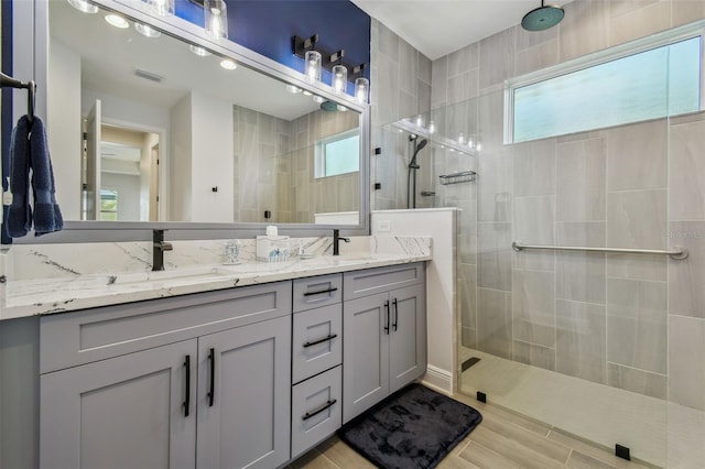 bathroom with double vanity, walk in shower, and a sink