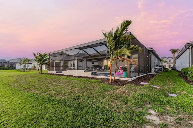 rear view of property with a lanai, a lawn, an outdoor pool, and a patio