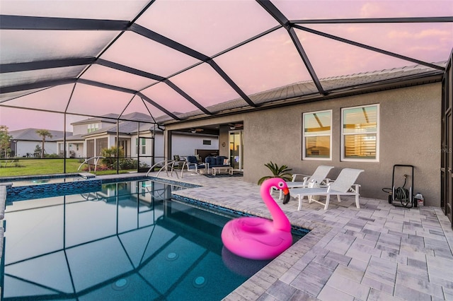 view of pool featuring glass enclosure, a pool with connected hot tub, and a patio area