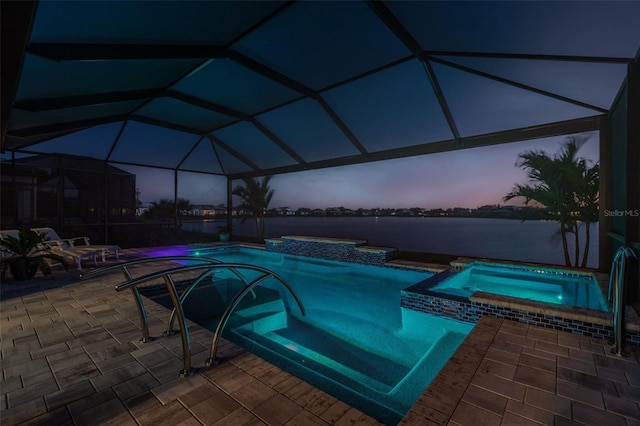 pool at dusk featuring a patio area, a pool with connected hot tub, and a lanai