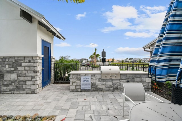 view of patio featuring area for grilling, fence, and an outdoor kitchen