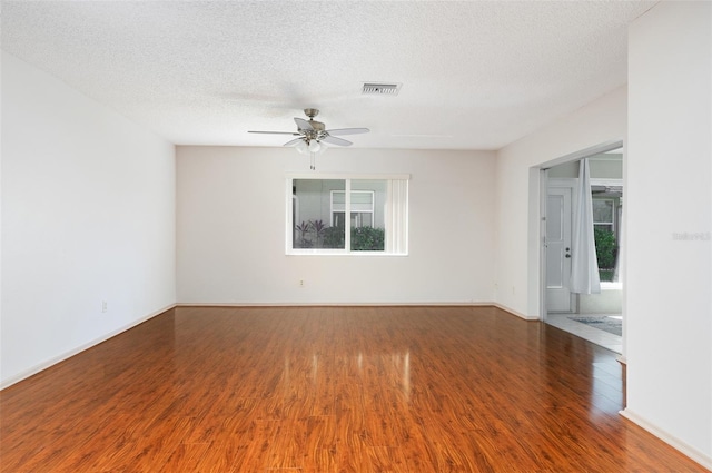 spare room featuring ceiling fan, visible vents, a textured ceiling, and wood finished floors