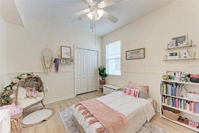 bedroom featuring ceiling fan, a closet, light wood-style flooring, and baseboards