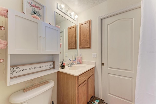 bathroom with toilet, a textured ceiling, and vanity