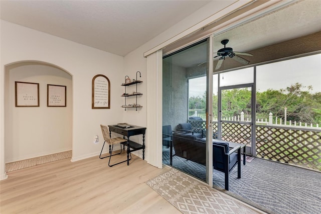 sitting room with wood finished floors, a ceiling fan, and baseboards