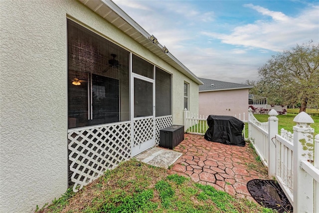 view of patio featuring grilling area, fence, a sunroom, and a ceiling fan