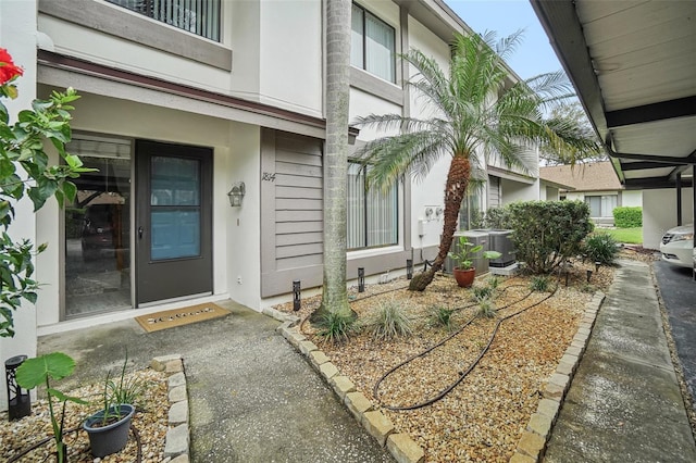 view of exterior entry with central AC unit and stucco siding