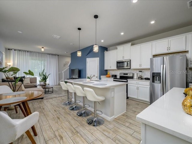 kitchen featuring stainless steel appliances, tasteful backsplash, wood tiled floor, and white cabinetry