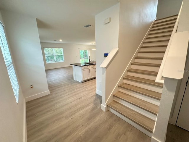 stairway featuring visible vents, baseboards, and wood finished floors