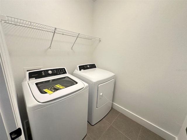 laundry area featuring laundry area, dark tile patterned flooring, washing machine and dryer, and baseboards