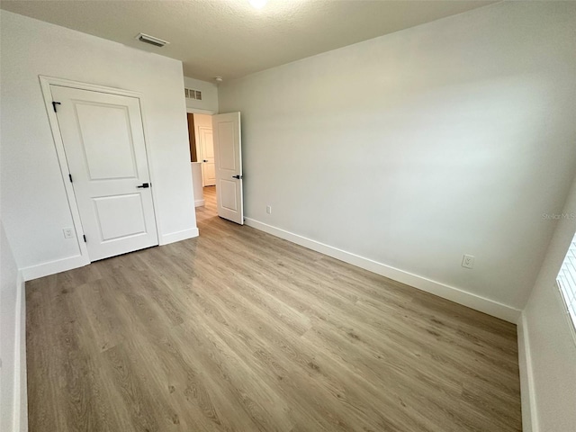 unfurnished bedroom featuring light wood-style flooring, visible vents, and baseboards