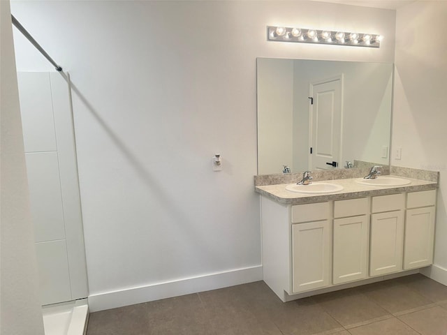 bathroom featuring tile patterned flooring, a sink, and baseboards