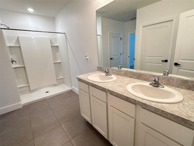 bathroom featuring double vanity, tile patterned flooring, a walk in shower, and a sink