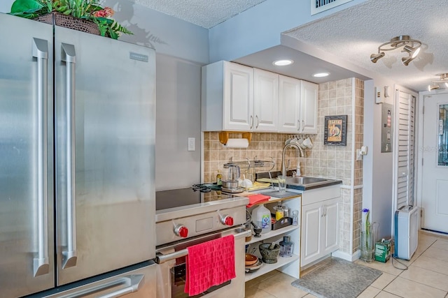 kitchen with light tile patterned floors, premium appliances, a sink, and white cabinetry