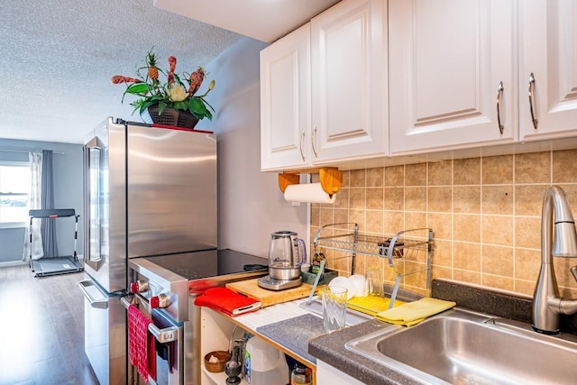 kitchen featuring wood finished floors, appliances with stainless steel finishes, a sink, and white cabinets