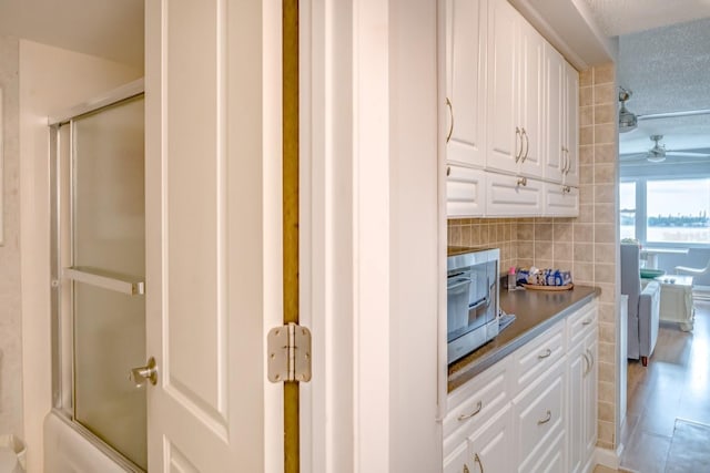 kitchen featuring tasteful backsplash, a ceiling fan, and white cabinets