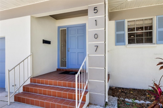 property entrance featuring a garage and stucco siding