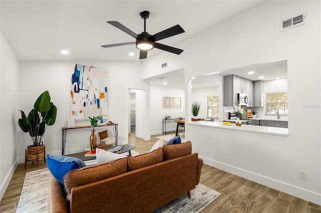 living area with light wood finished floors, visible vents, and baseboards