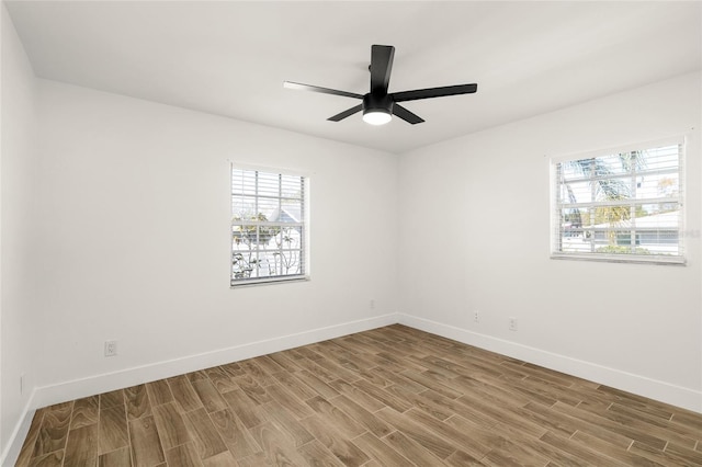 spare room featuring plenty of natural light, baseboards, and wood finished floors