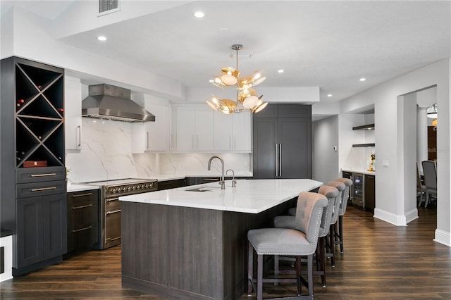 kitchen featuring premium appliances, open shelves, dark wood-style flooring, a sink, and wall chimney exhaust hood