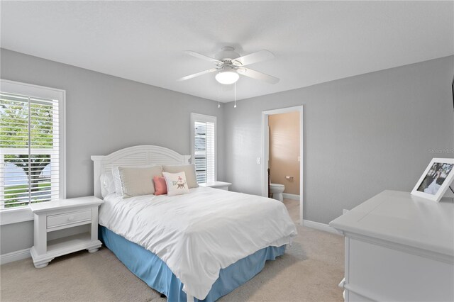 bedroom with light carpet, ceiling fan, connected bathroom, and baseboards