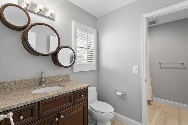 bathroom featuring visible vents, baseboards, vanity, and toilet