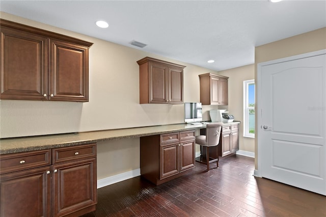 kitchen with dark wood-style flooring, visible vents, built in desk, and baseboards