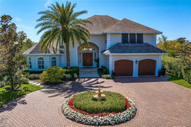 view of front of property with a garage, roof with shingles, decorative driveway, and stucco siding