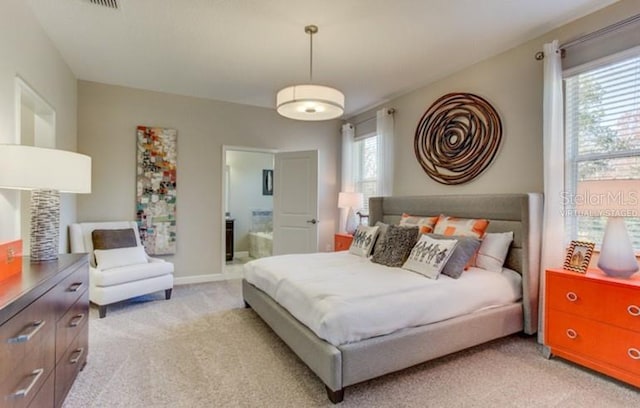 bedroom featuring ensuite bath, baseboards, and light colored carpet