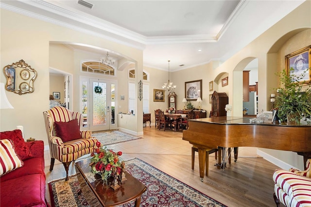 interior space with visible vents, crown molding, baseboards, a chandelier, and arched walkways