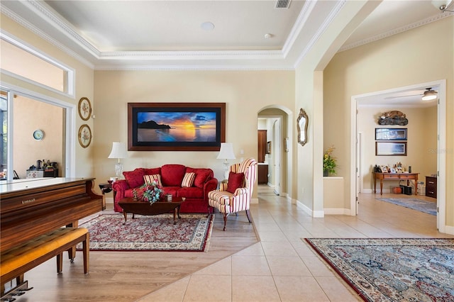 living area with ornamental molding, arched walkways, a high ceiling, light tile patterned floors, and baseboards