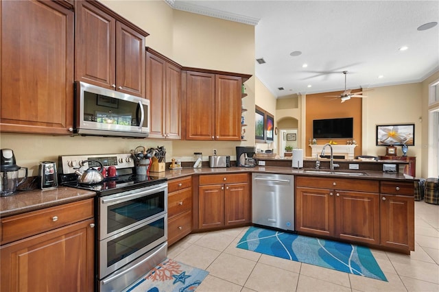 kitchen with a peninsula, light tile patterned flooring, appliances with stainless steel finishes, and a sink