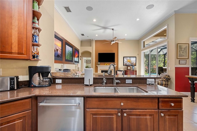 kitchen with dark stone countertops, brown cabinetry, visible vents, a sink, and crown molding